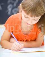 Little girl is writing using a pen