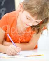 Little girl is writing using a pen