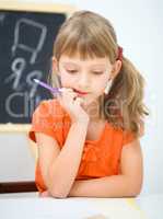 Little girl is writing using a pen