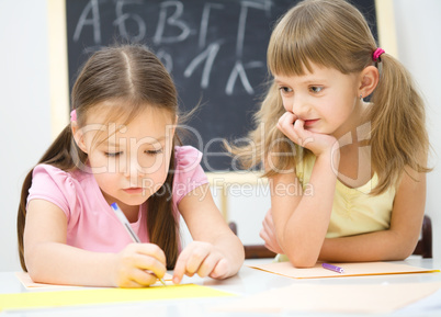 Little girls are writing using a pen