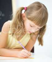 Little girl is writing using a pen