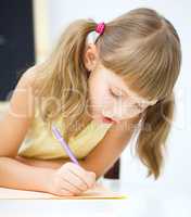 Little girl is writing using a pen