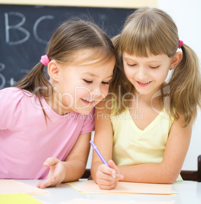 Little girls are writing using a pen