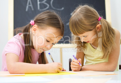 Little girls are writing using a pen