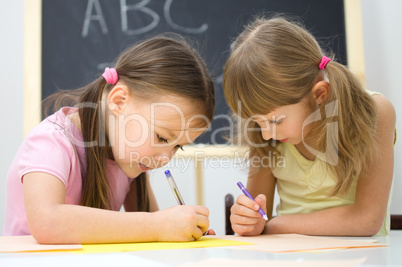 Little girls are writing using a pen