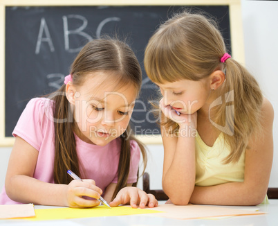 Little girls are writing using a pen