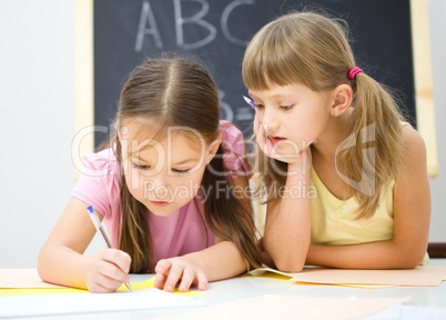 Little girls are writing using a pen