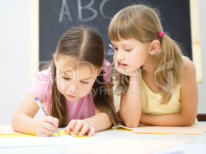 Little girls are writing using a pen