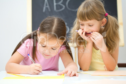 Little girls are writing using a pen