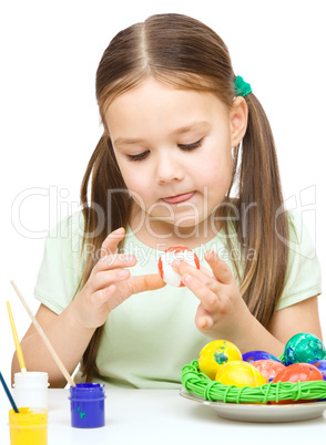 Little girl is painting eggs preparing for Easter