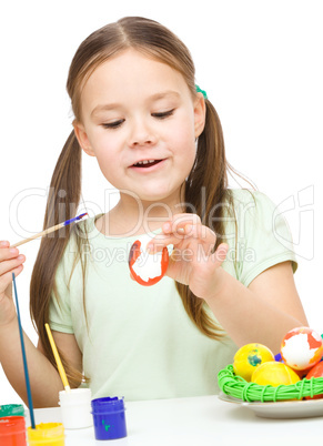 Little girl is painting eggs preparing for Easter