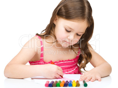 Little girl is drawing using a crayon