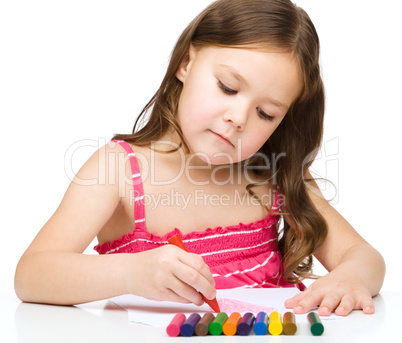 Little girl is drawing using a crayons