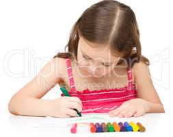 Little girl is drawing using a crayon