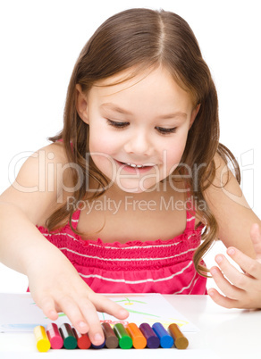 Little girl is drawing using colorful crayons