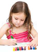 Little girl is drawing using a crayon