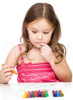 Little girl is drawing using colorful crayons