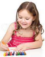 Little girl is drawing using colorful crayons