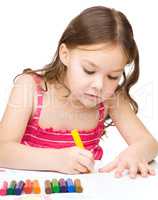 Little girl is drawing using a crayons