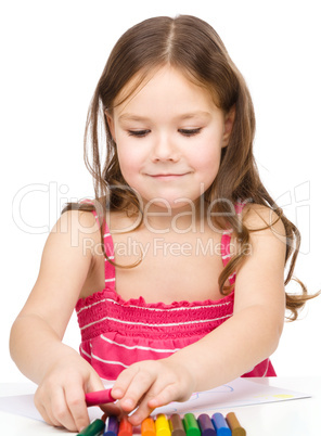 Little girl is drawing using colorful crayons