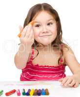 Little girl is drawing using colorful crayons