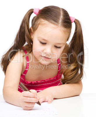 Little girl is drawing using a crayon