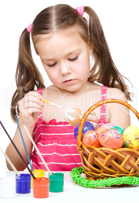 Little girl is painting eggs preparing for Easter