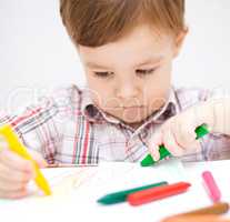 Little boy is drawing on white paper