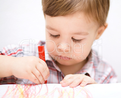 Little boy is drawing on white paper