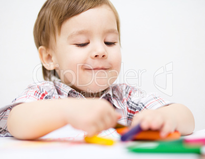 Little boy is drawing on white paper