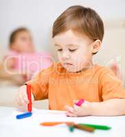 Little boy is drawing on white paper