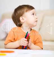 Little boy is drawing on white paper