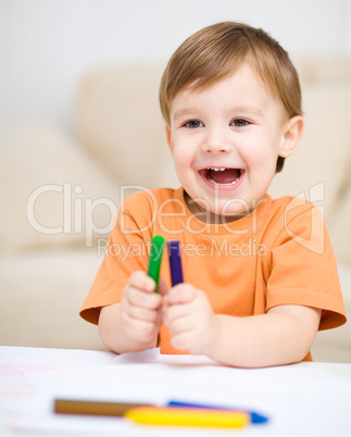 Little boy is drawing on white paper