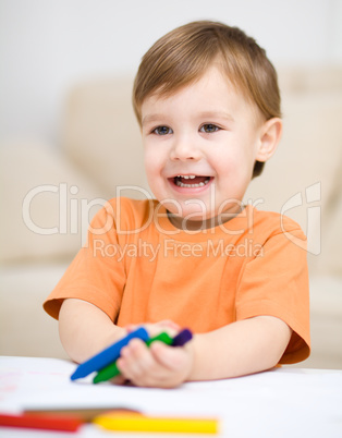 Little boy is drawing on white paper