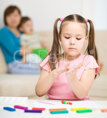 Little girl is playing with plasticine