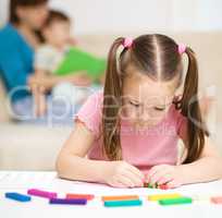 Little girl is playing with plasticine