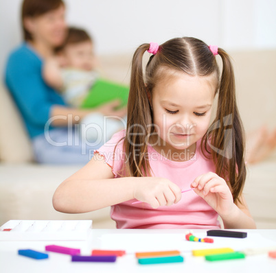 Little girl is playing with plasticine