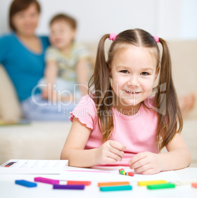 Little girl is playing with plasticine