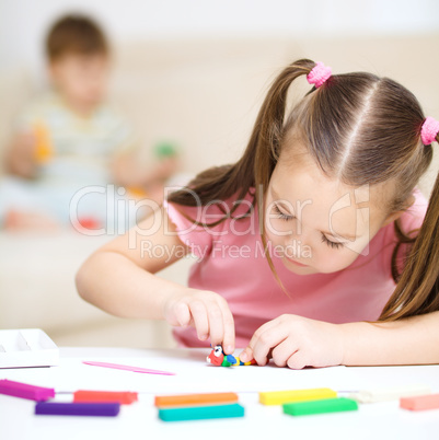 Little girl is playing with plasticine