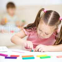 Little girl is playing with plasticine