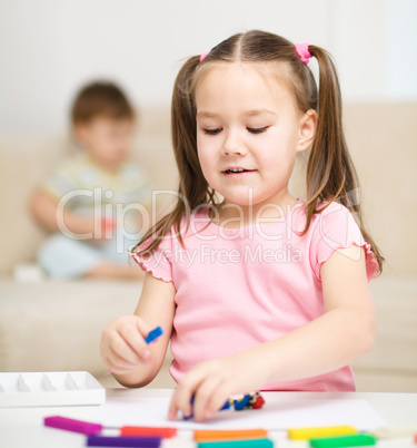 Little girl is playing with plasticine