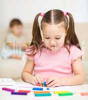 Little girl is playing with plasticine