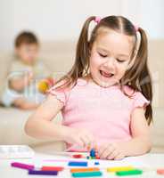 Little girl is playing with plasticine