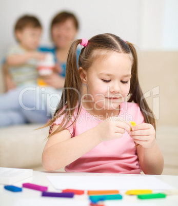 Little girl is playing with plasticine