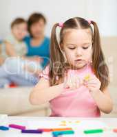 Little girl is playing with plasticine