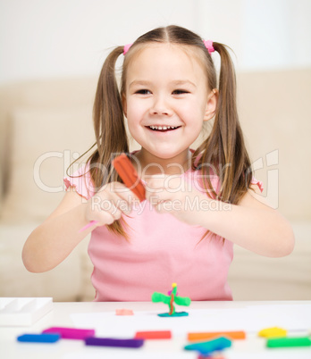 Little girl is playing with plasticine