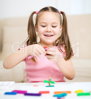 Little girl is playing with plasticine