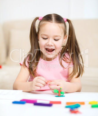 Little girl is playing with plasticine