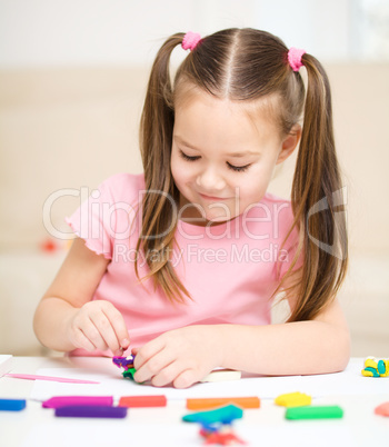 Little girl is playing with plasticine