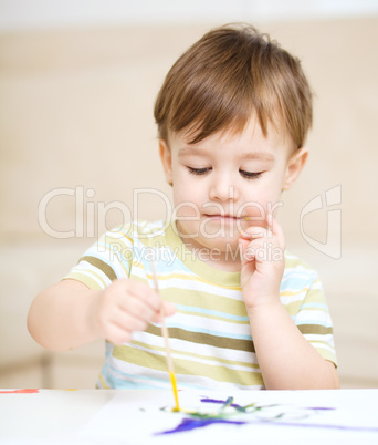 Little boy is playing with paints